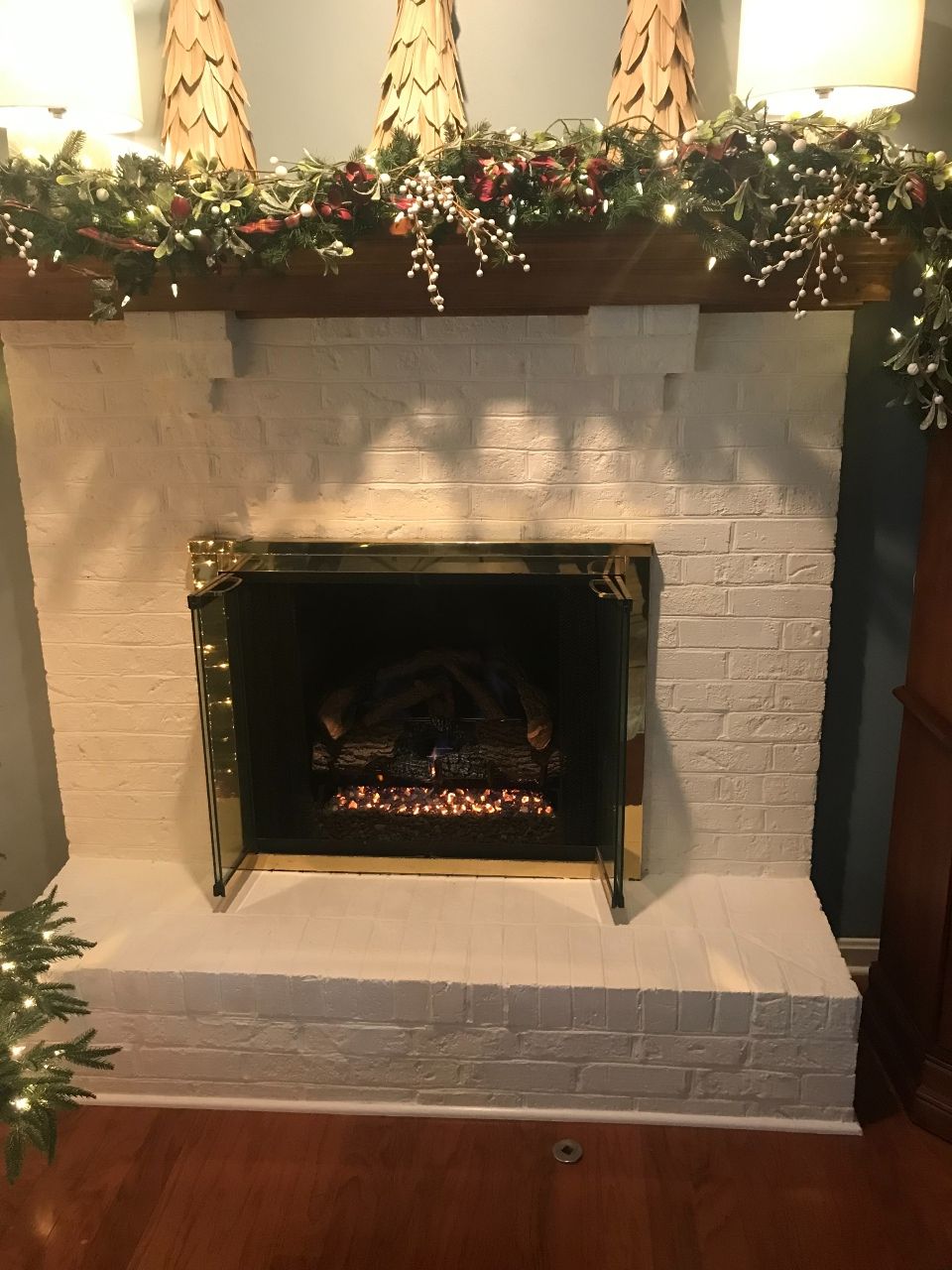 A white brick fireplace with a mantle decorated for christmas