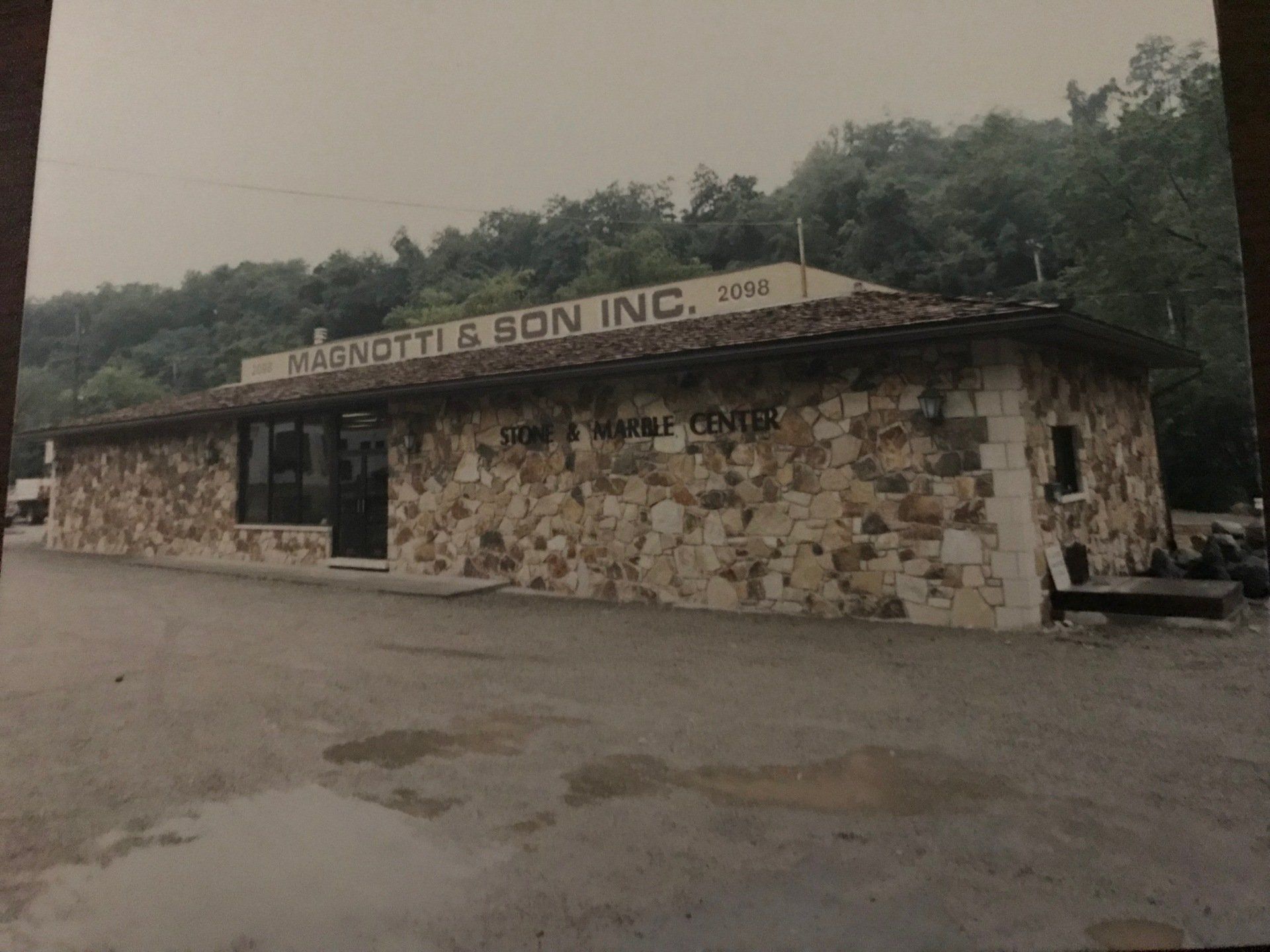 A black and white photo of a stone building with a sign that says ' raschett & son inc ' on it.