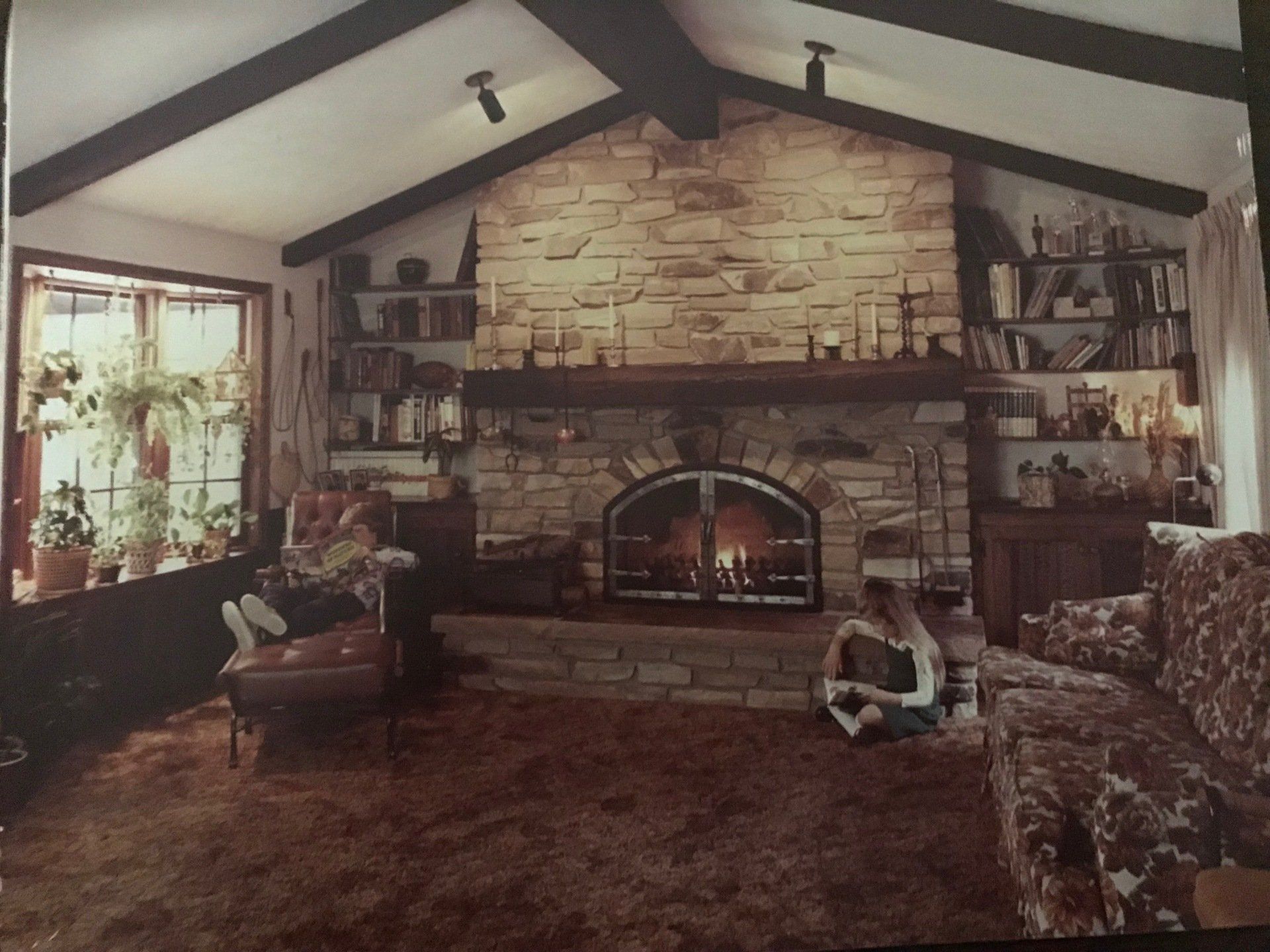 A living room with a brick fireplace and a vaulted ceiling