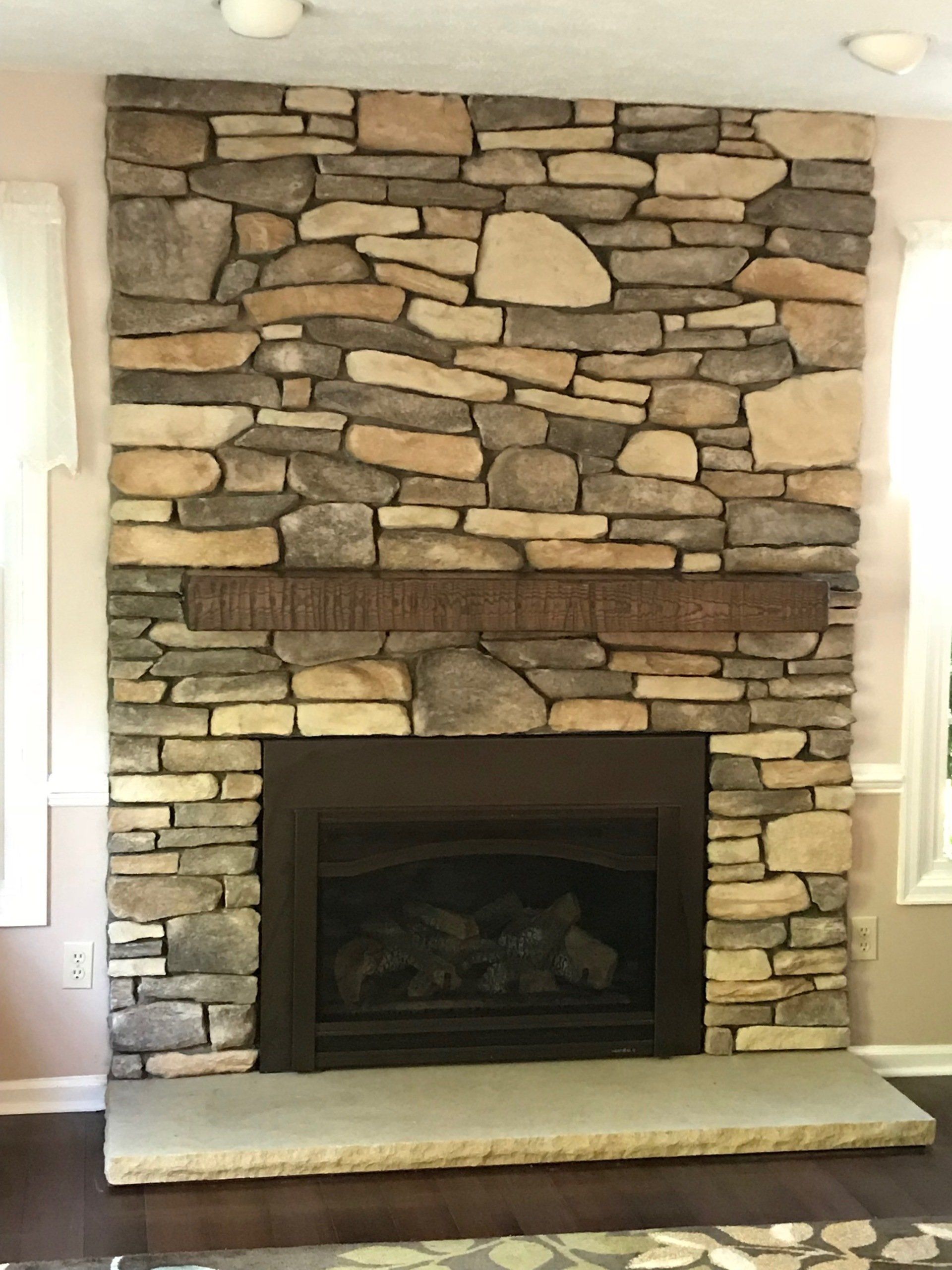 A living room with a stone fireplace and a window