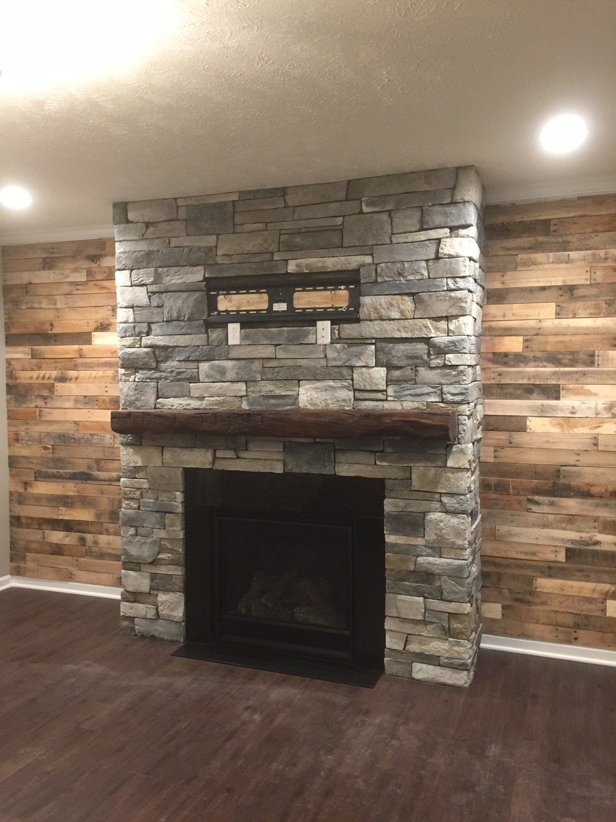 A stone fireplace with a wooden mantle in a living room