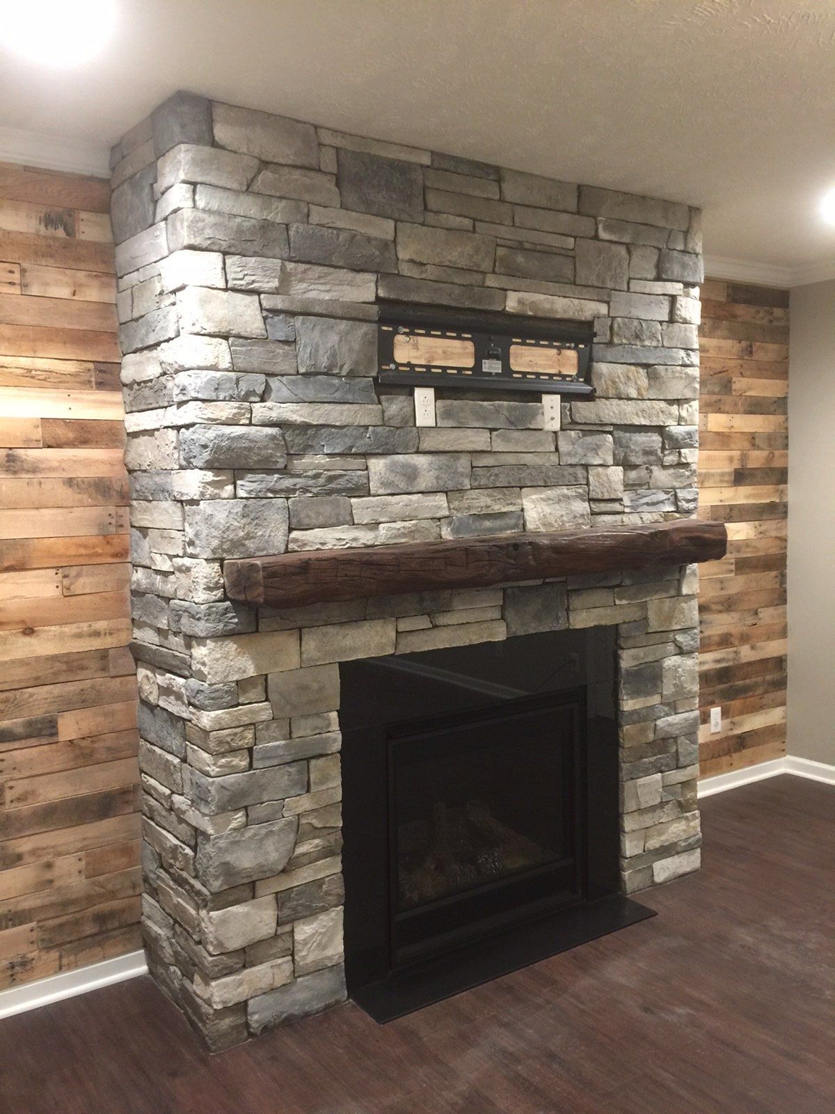 A stone fireplace with a wooden mantle in a living room.
