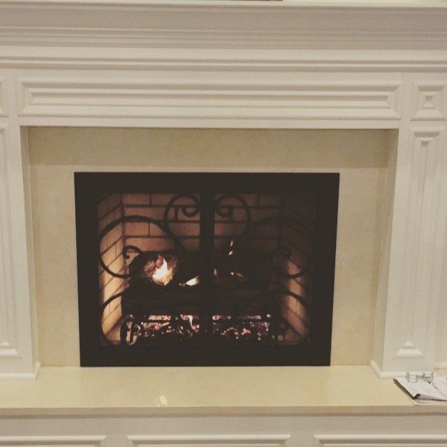 A fireplace with a wrought iron screen on it