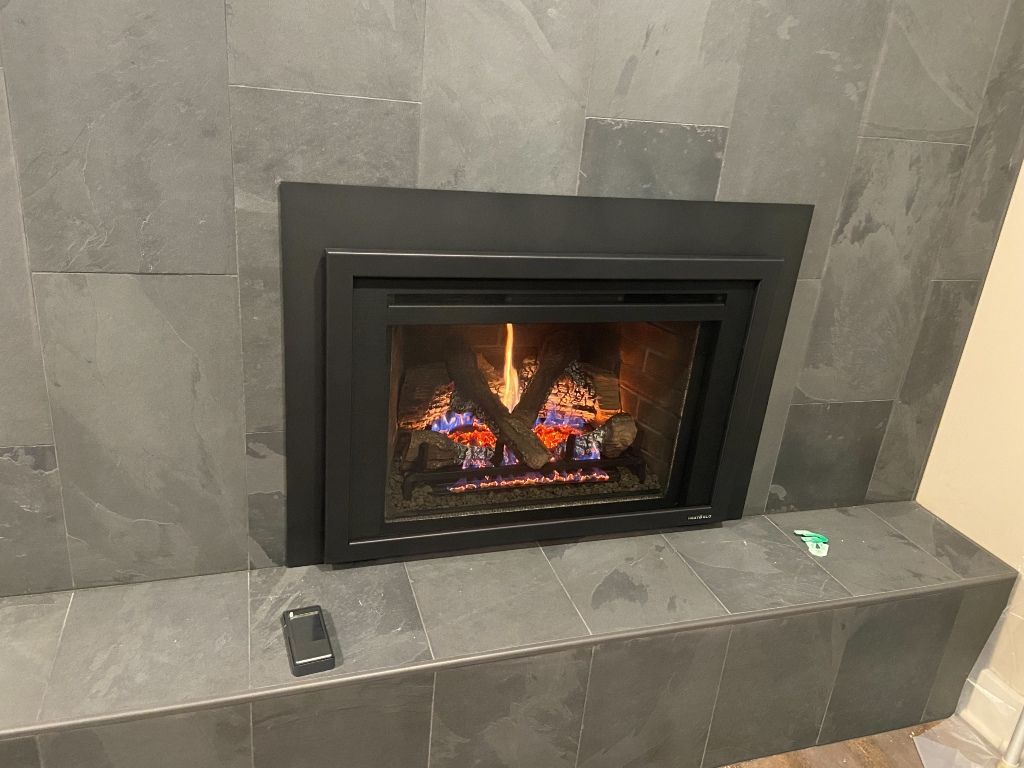 A fireplace is sitting on a tiled ledge in a living room.