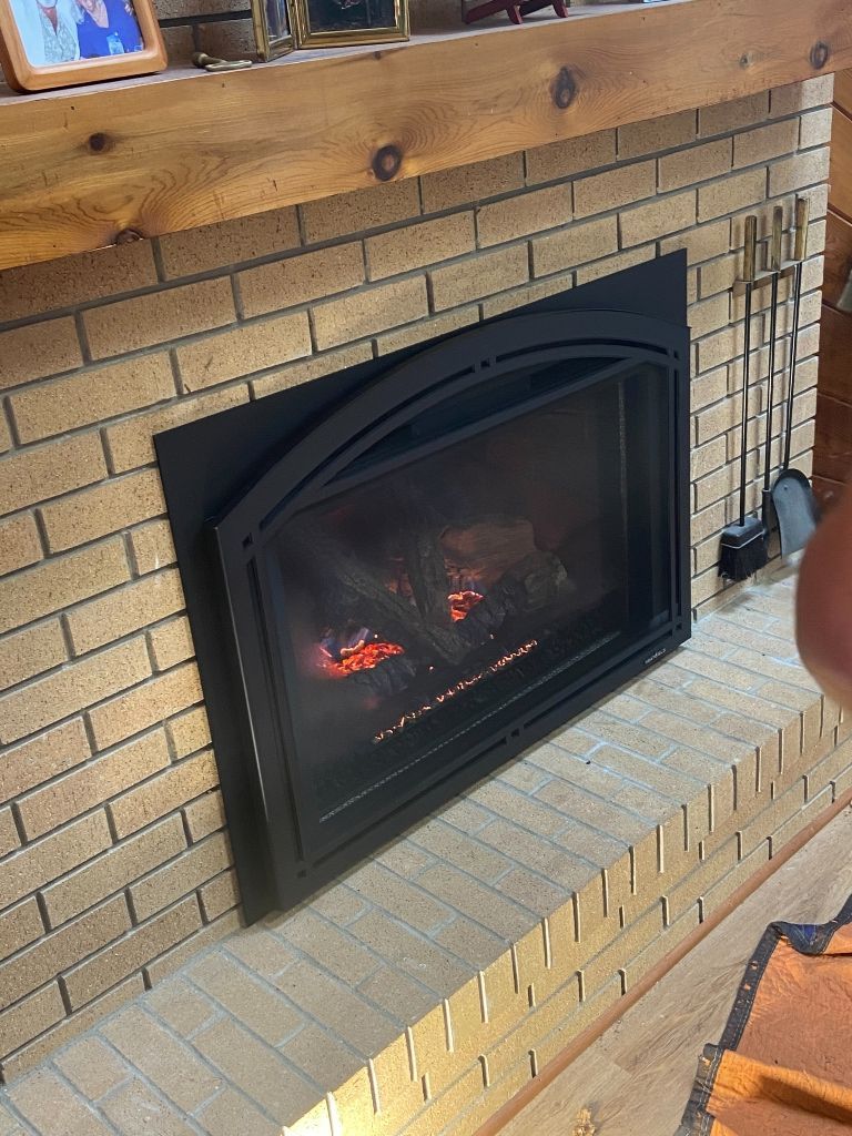 A fireplace in a living room with a wooden mantle.