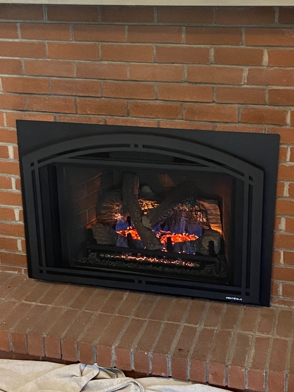 A brick fireplace with a black fireplace insert.