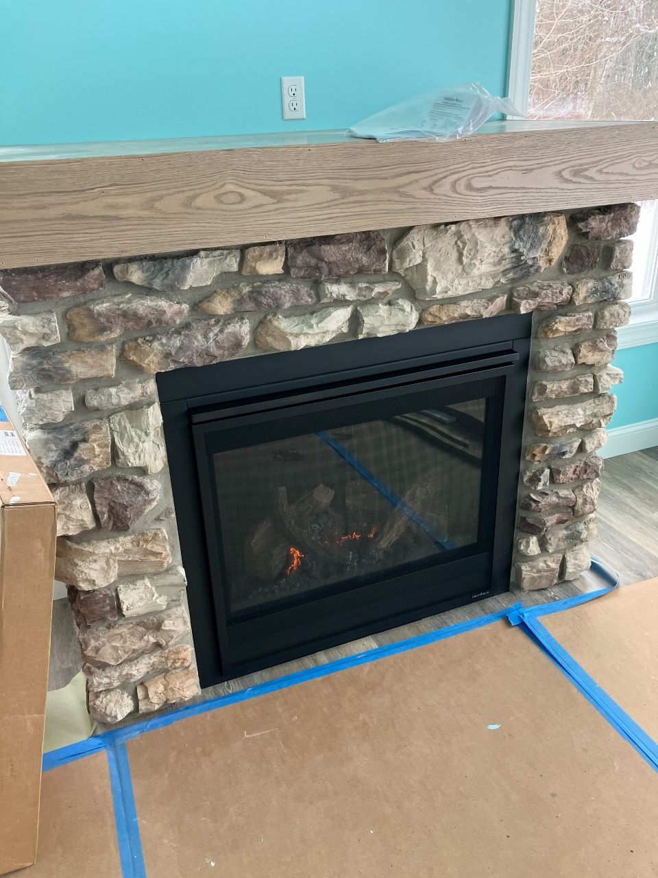 A fireplace with a stone mantle and a gas fireplace in a living room.