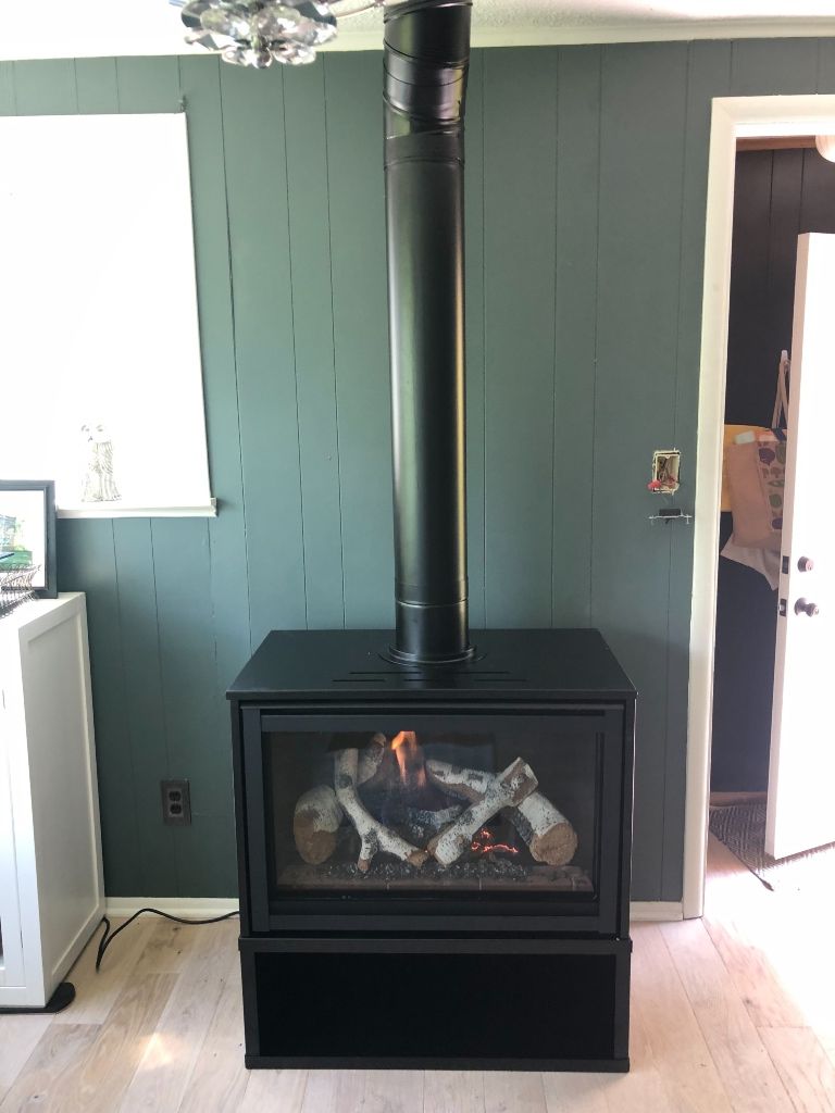 A gas fireplace is sitting in a living room next to a window.