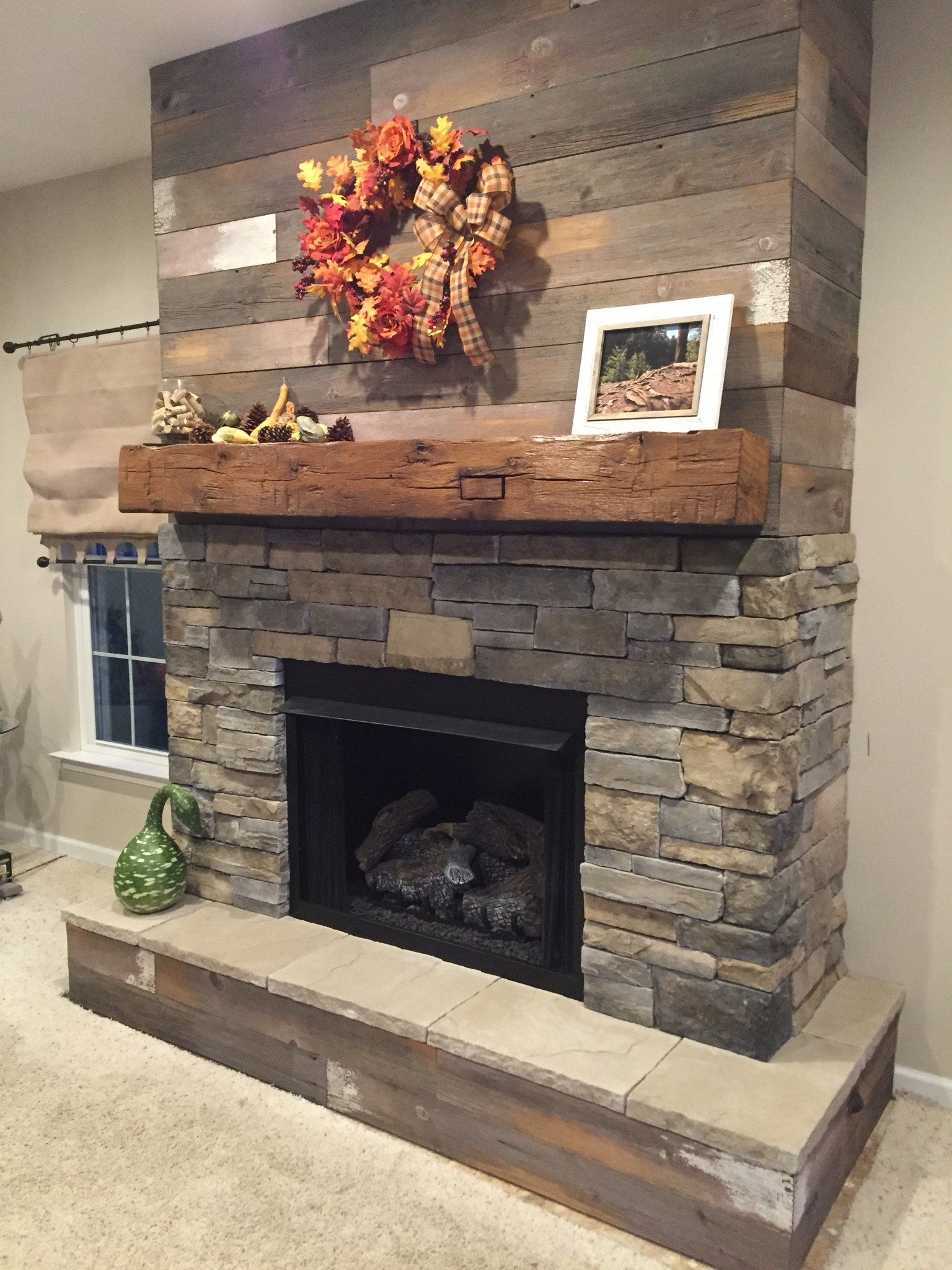 A living room with a stone fireplace and a wooden mantle.