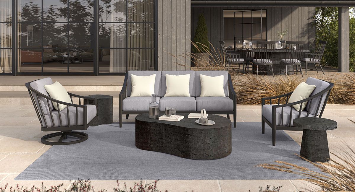 A patio with a couch , chairs , tables and a rug.