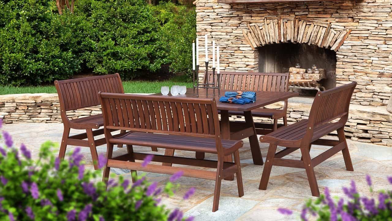 A wooden patio set with a table and benches in front of a stone fireplace.