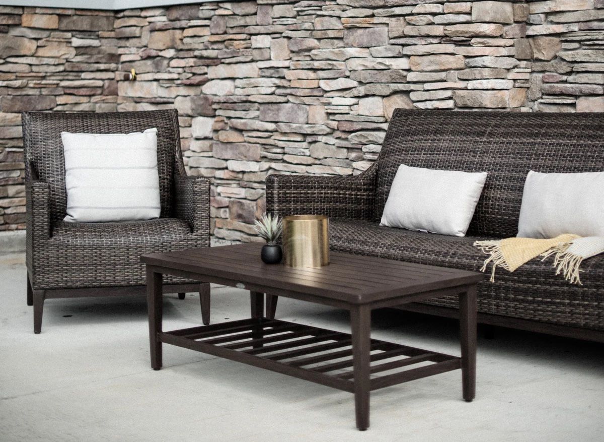 A patio with a couch , chairs , and a coffee table.