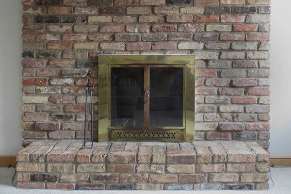 A brick fireplace with a brass door in a living room.