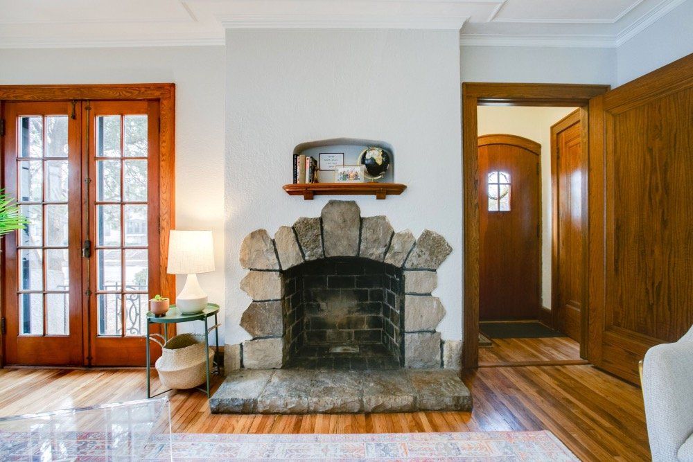 A living room with a stone fireplace and french doors.