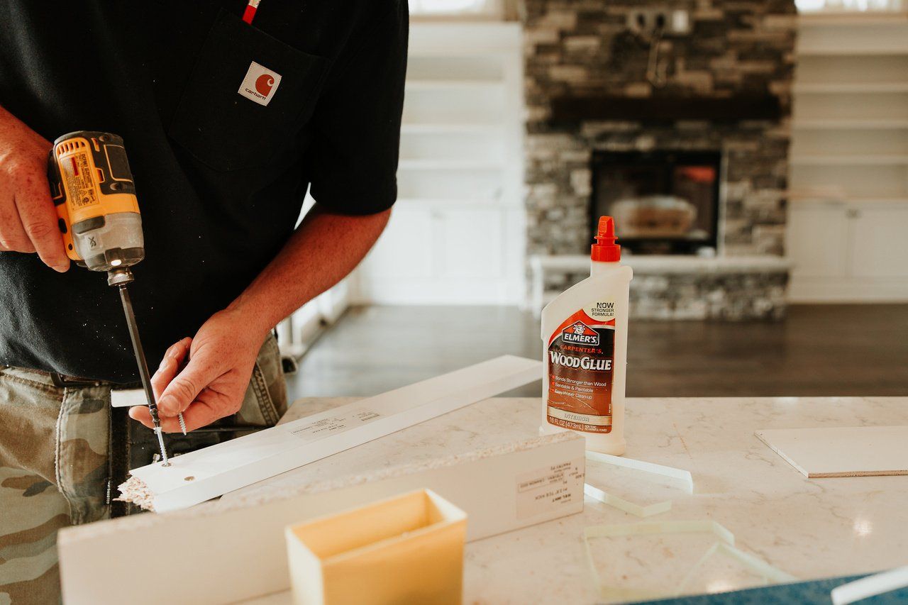 A man is using a drill to drill a hole in a piece of wood.