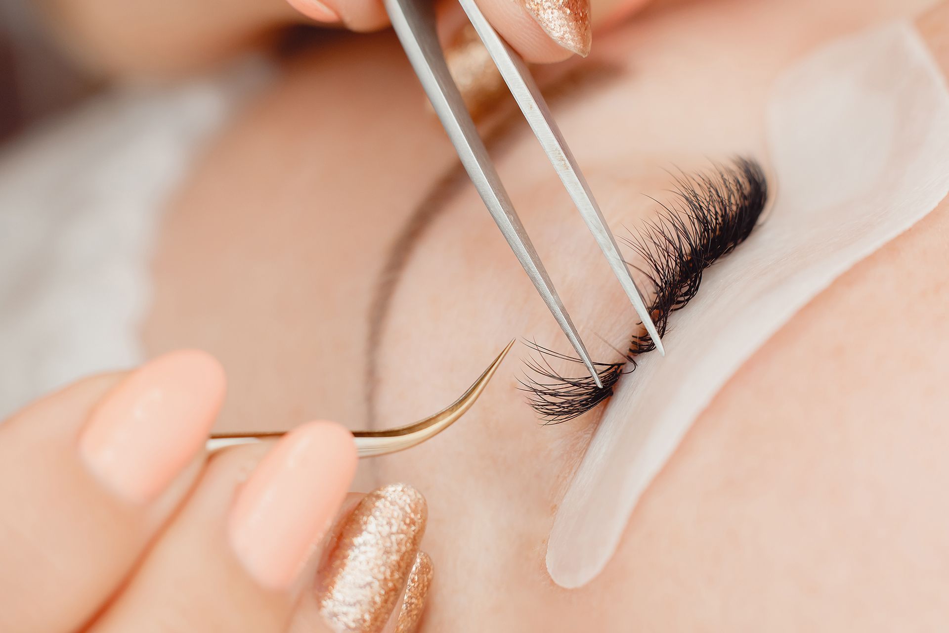 A woman is getting her eyelashes done by a makeup artist.