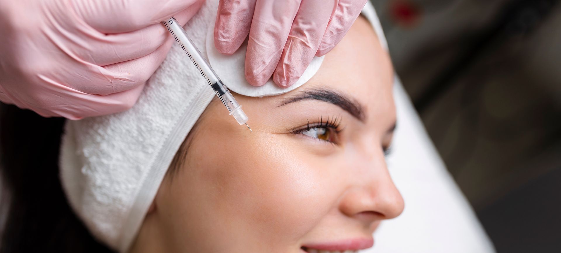 A woman is getting a botox injection in her forehead.