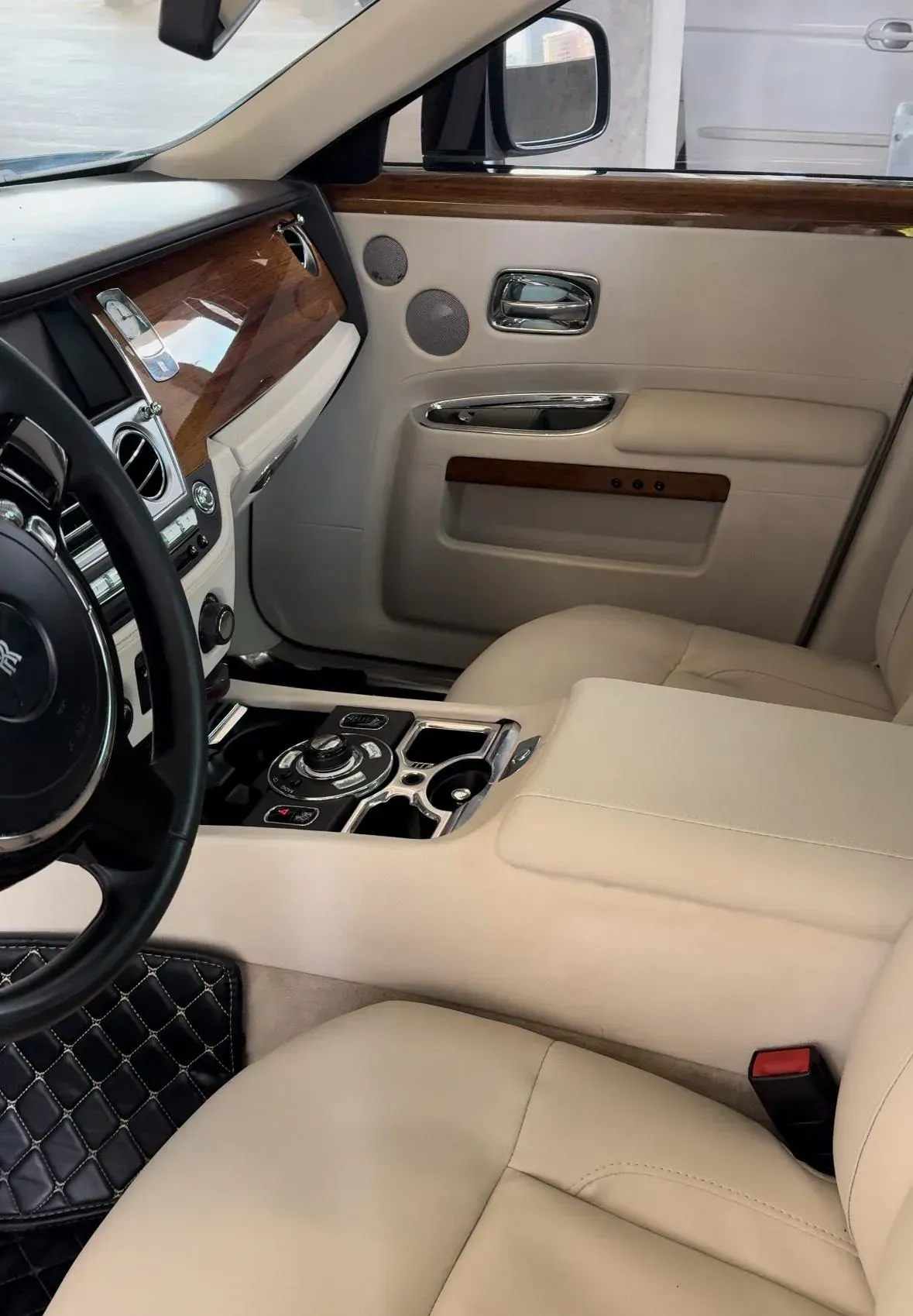 Luxury car interior with beige leather seats, wood trim, and center console.