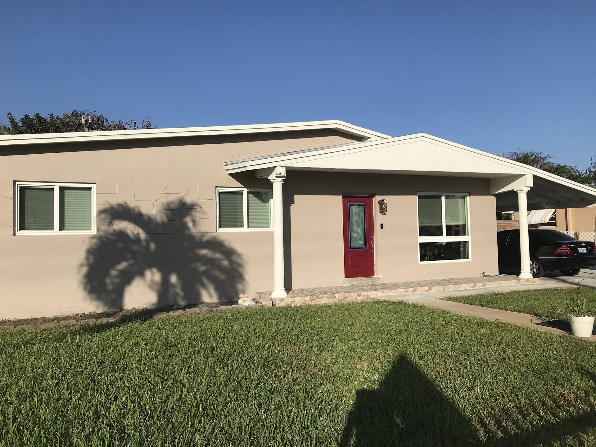 A house with a red door and a car parked in front of it.