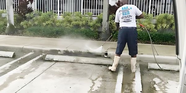 A man is using a high pressure washer to clean a parking lot.