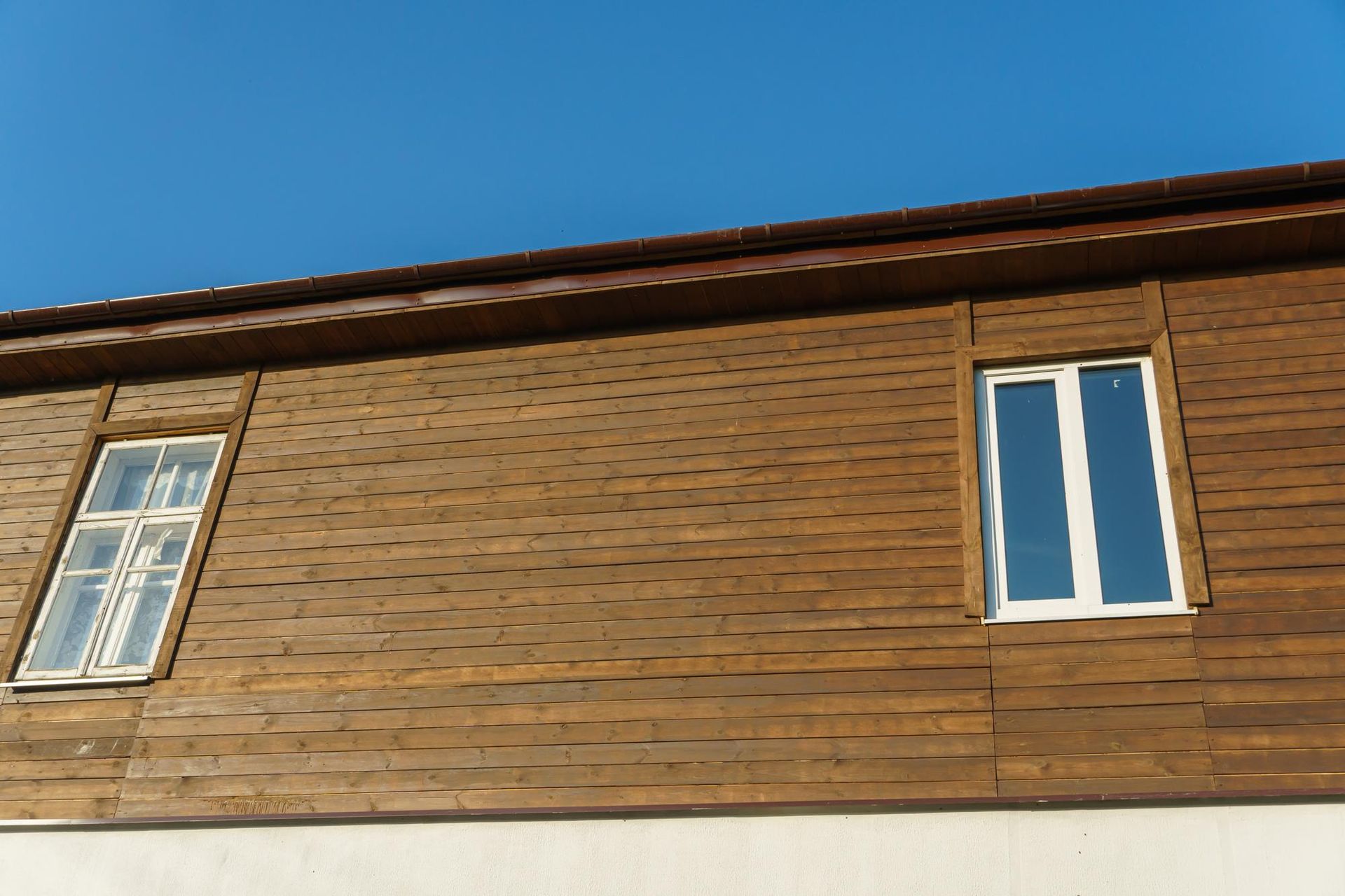 a wooden building with two windows and a blue sky in the background