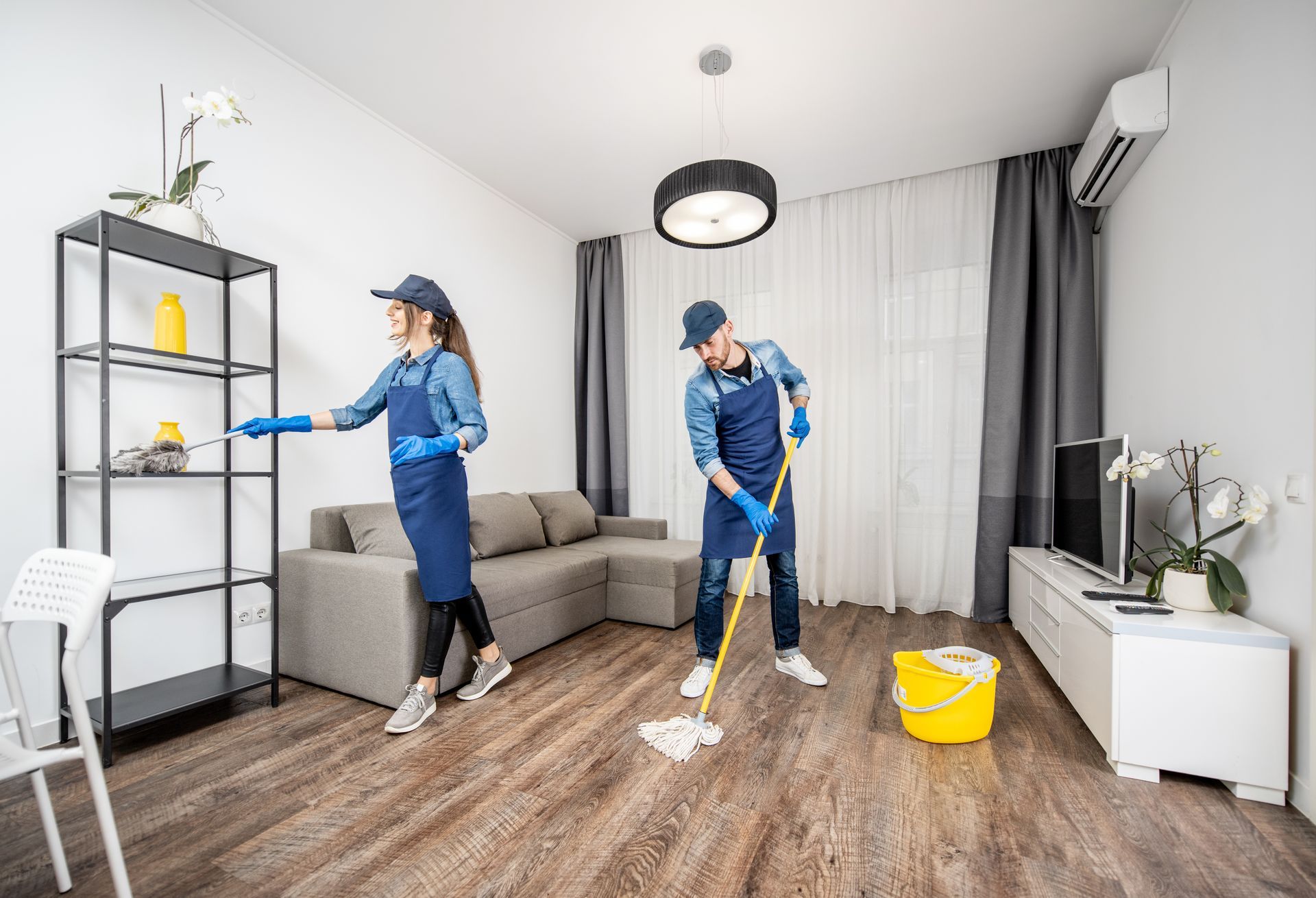 A man and a woman are cleaning a living room.
