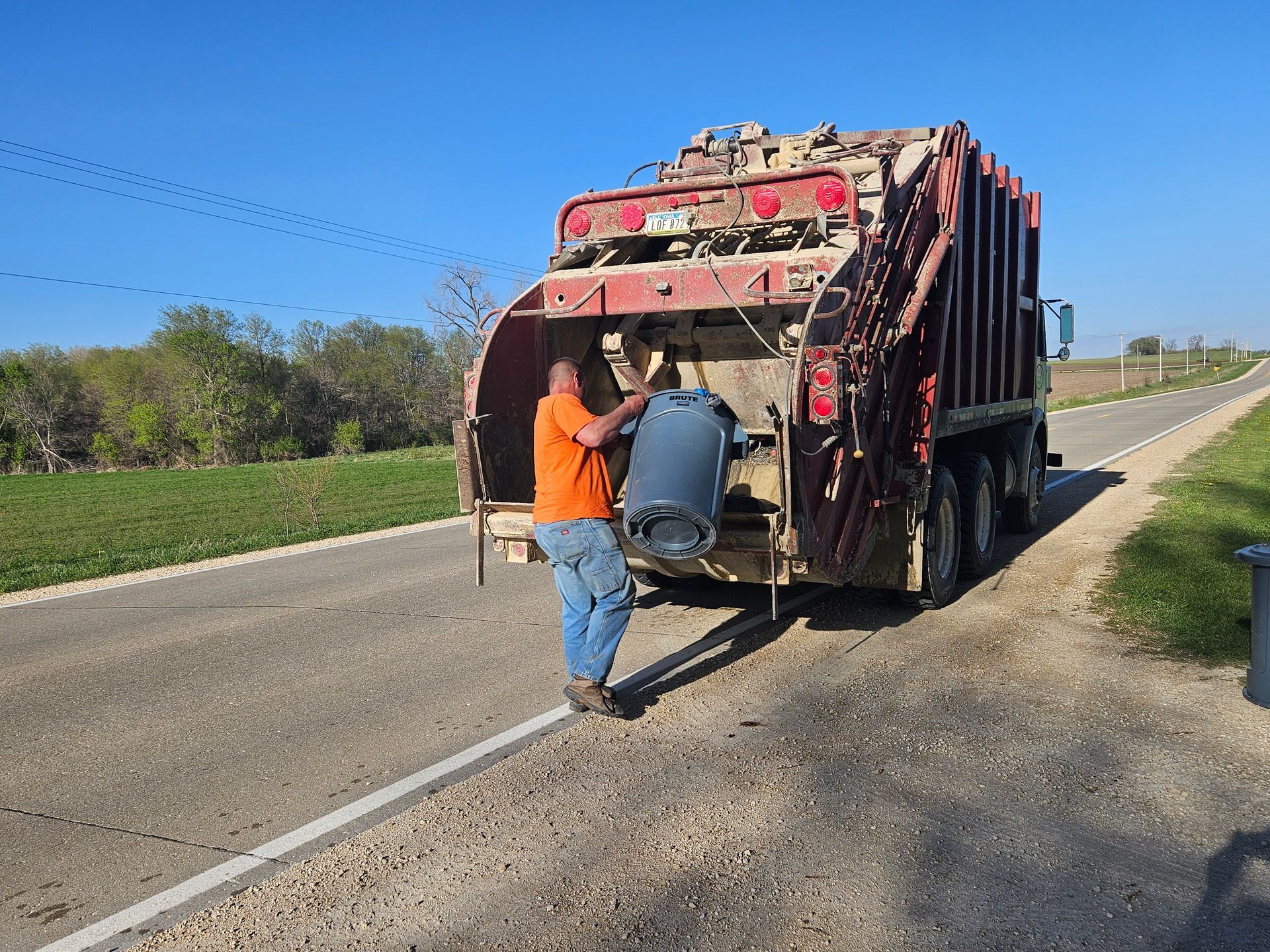 Man Dumping Trash Can on the Dump Truck — Prairieburg, IA — L & R Dumpsters