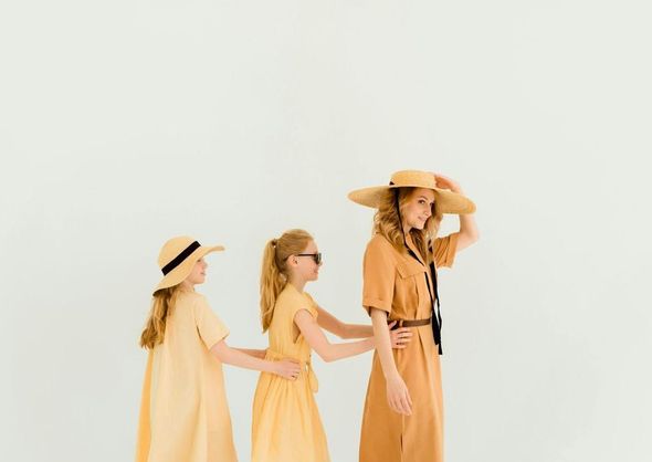 A woman and two girls are standing next to each other on a white background.