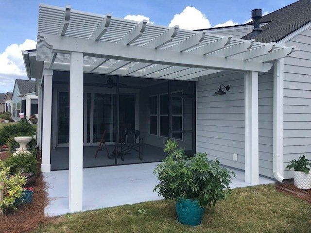 Pergola installation including white pillars over a concrete slab