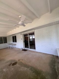 Covered patio with a ceiling fan, sliding glass door, and white brick wall.
