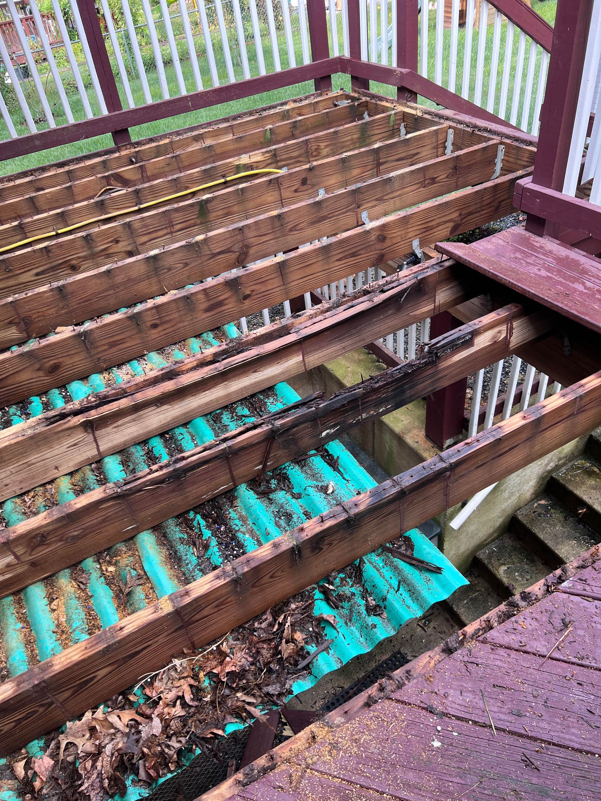 Deconstructed wooden deck showing joists, insulation, and debris.