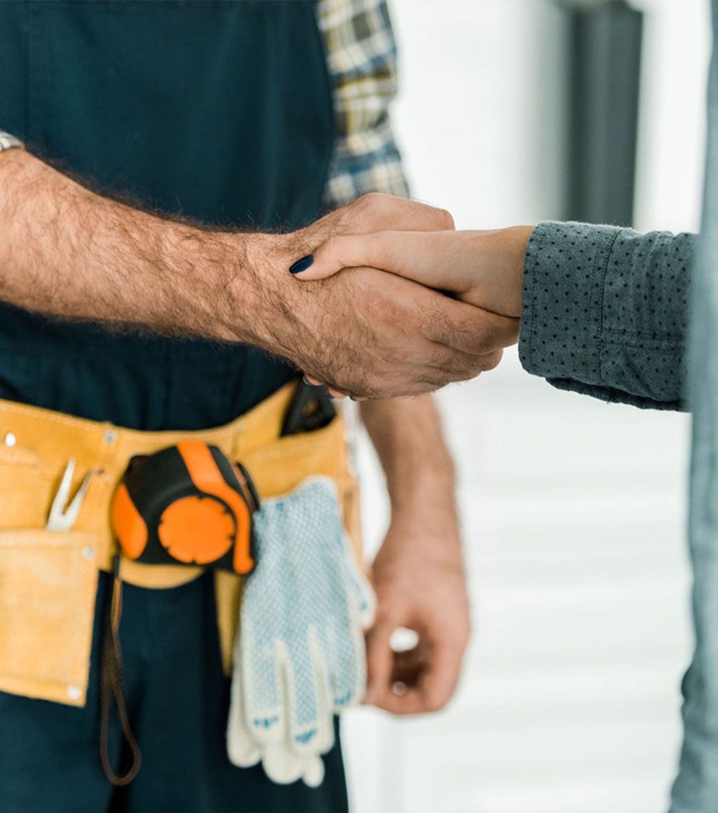 A man in a blue vest is shaking hands with a woman.