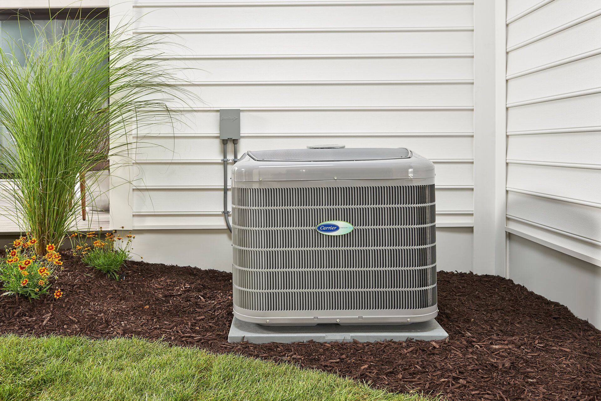 A man is holding a little girl in his arms in front of an air conditioner.