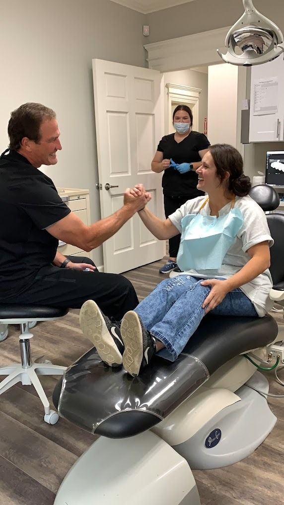 Dentist pointing at teeth on a screen during a consultation in an office.