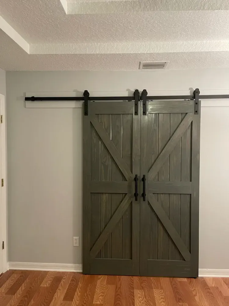 A pair of sliding barn doors in a room with hardwood floors.