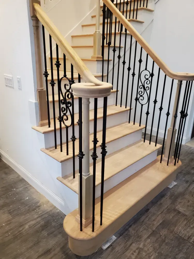 A wooden staircase with a wrought iron railing in a house.