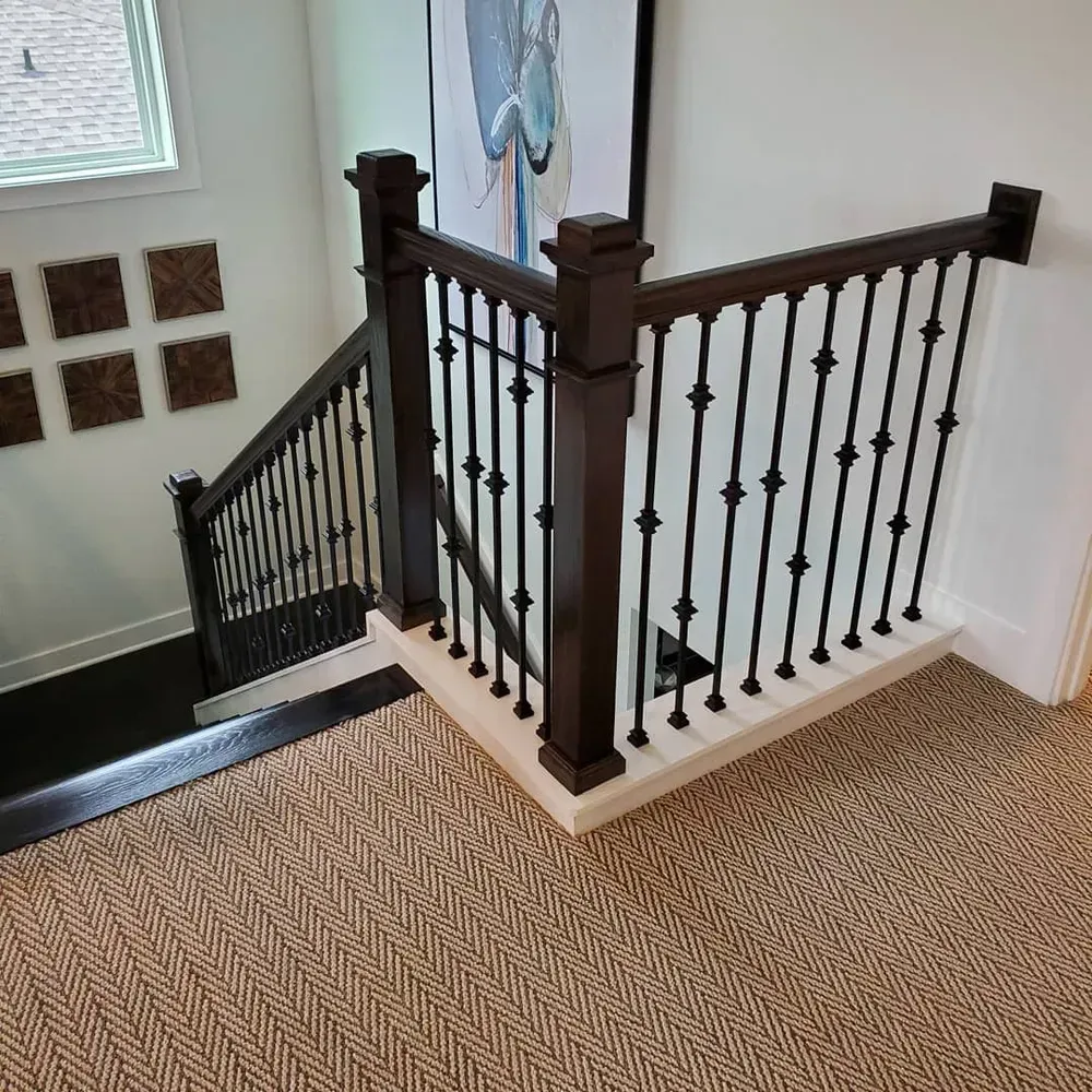 A staircase with a wrought iron railing and a picture on the wall.