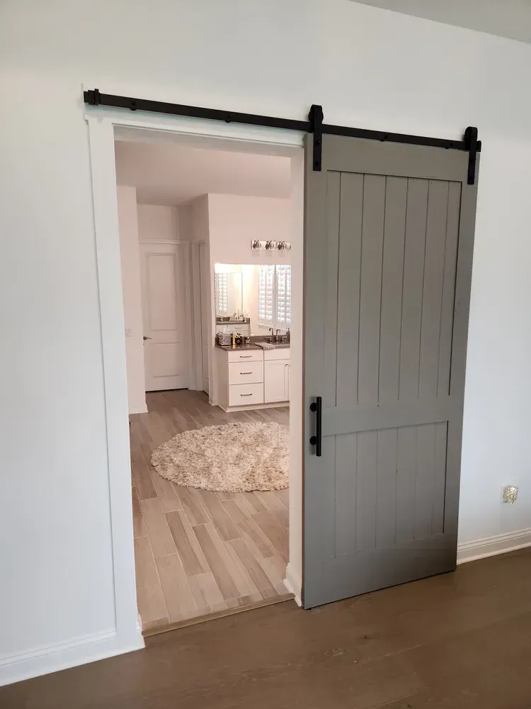 A sliding barn door is open to a bathroom in a house.
