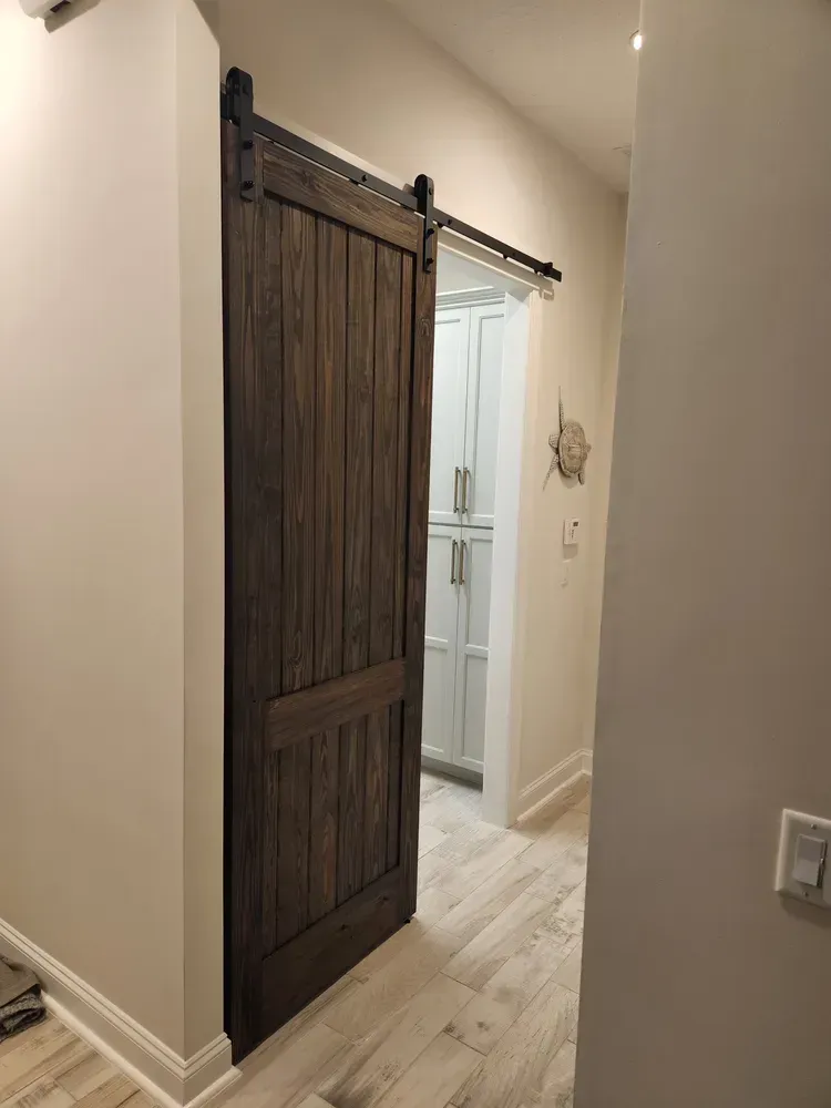 A sliding barn door in a hallway leading to a kitchen.