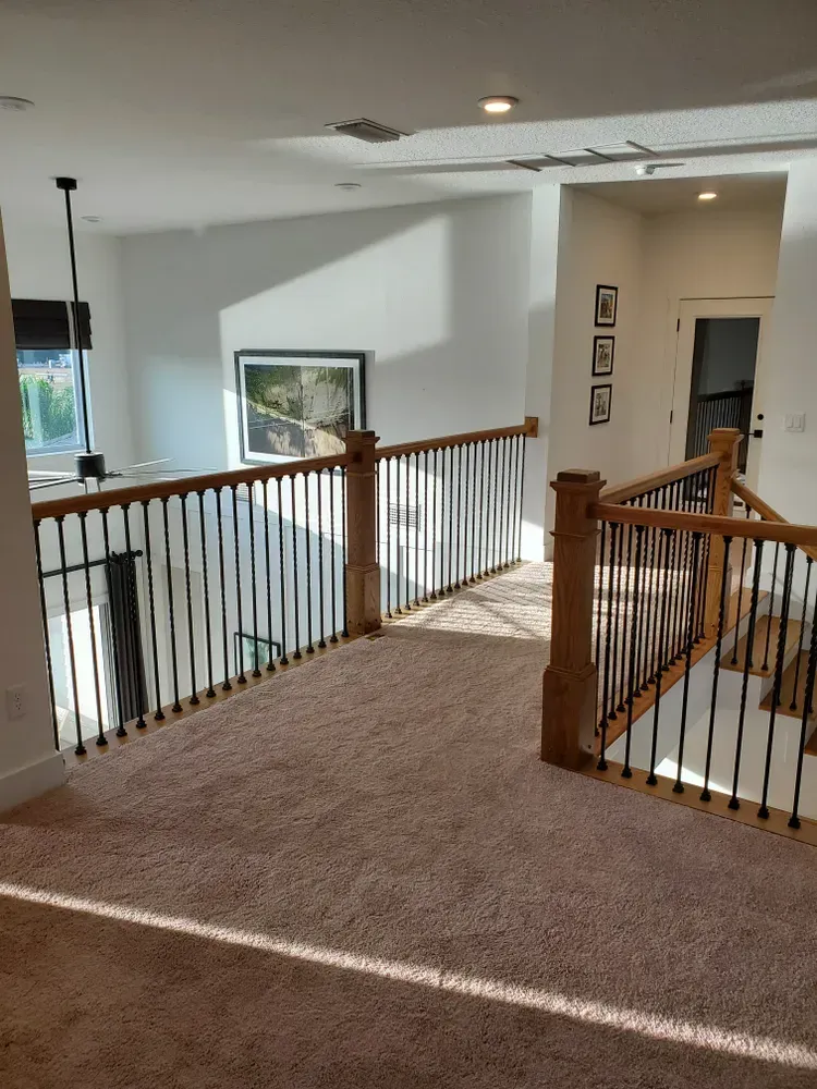 A staircase in a house with a wooden railing and a carpeted floor.