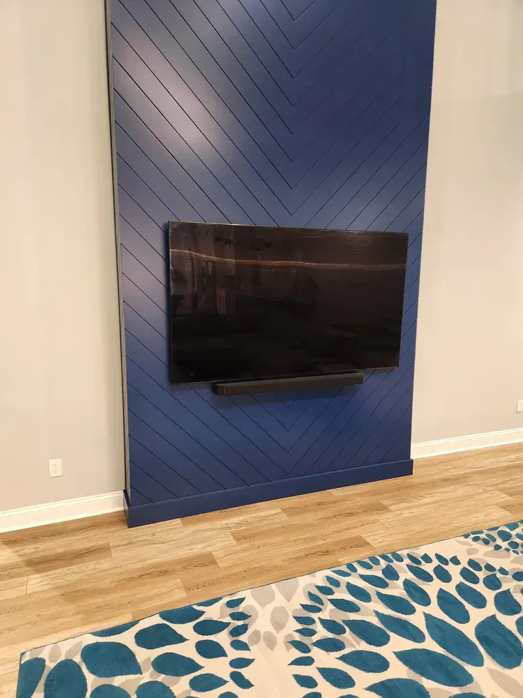A flat screen tv is mounted on a blue wall in a living room.