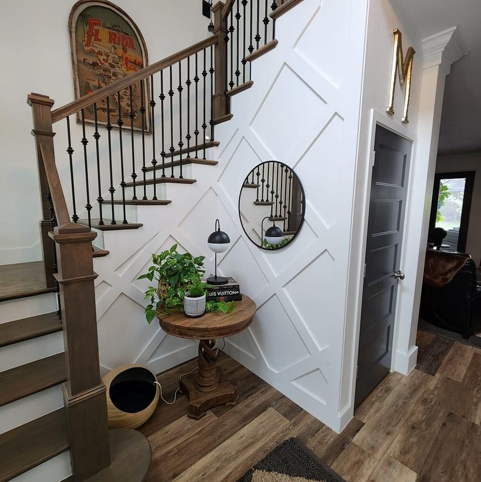A hallway with stairs and a table with a plant on it