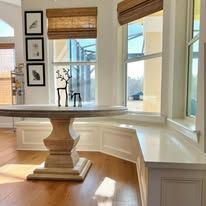 There is a table in the middle of the room next to a window.