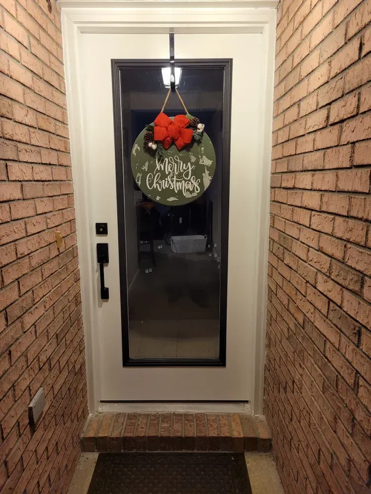 A white door with a christmas wreath hanging on it.