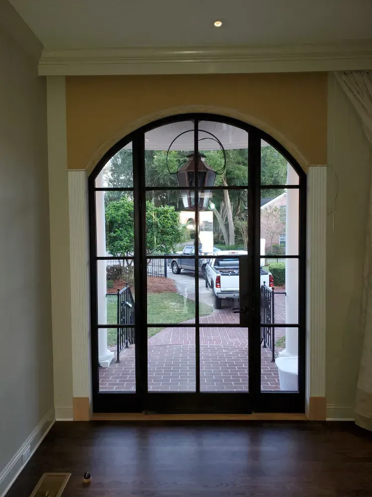A room with a large arched window looking out to a driveway