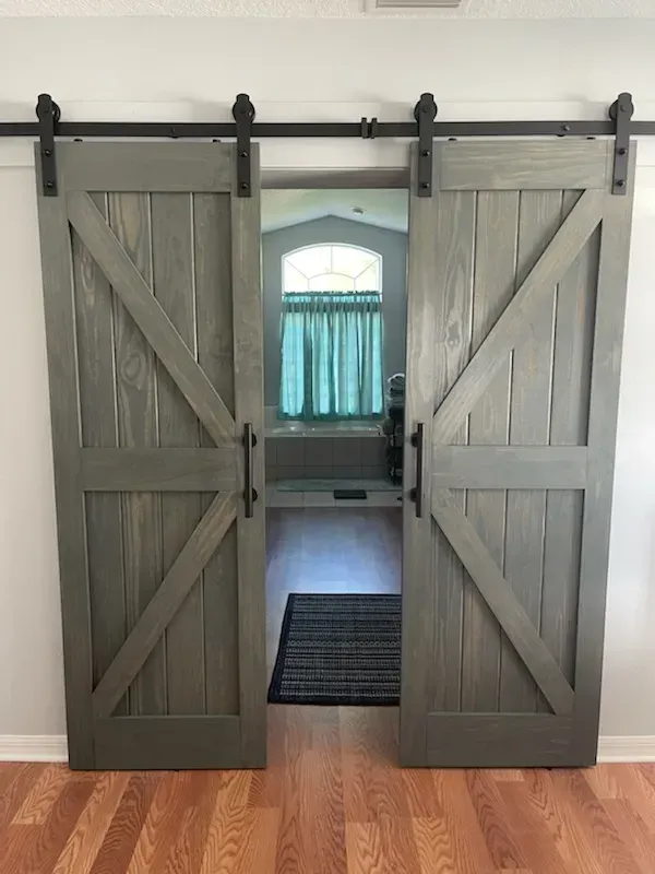 A pair of gray sliding barn doors open to a bathroom.