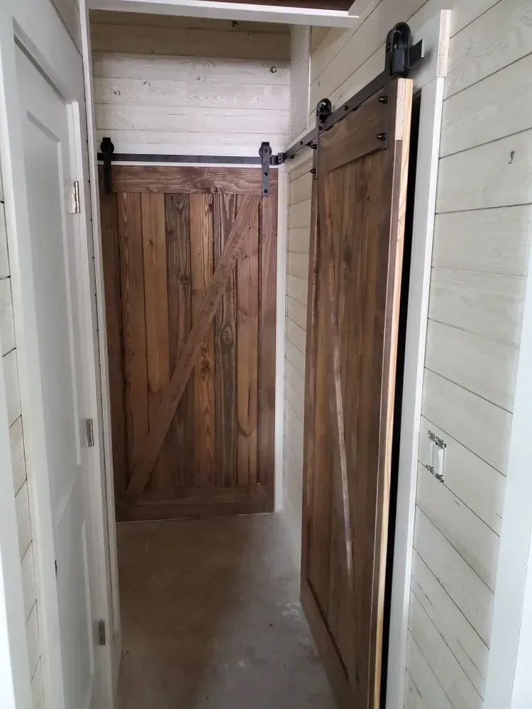 A hallway with a sliding barn door in the middle of it.