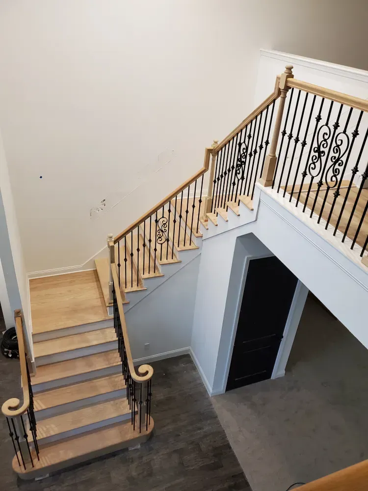 An aerial view of a wooden staircase with a wrought iron railing.