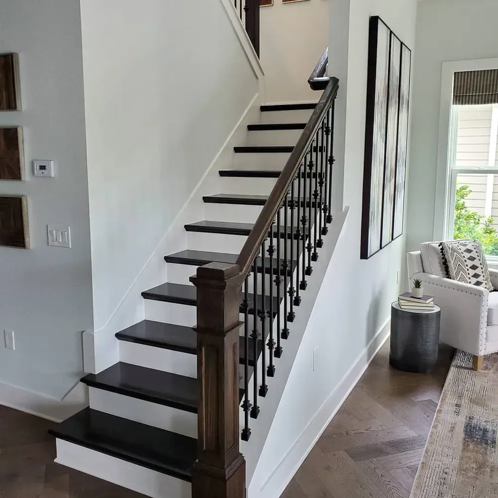 A black and white staircase with a wooden railing in a living room
