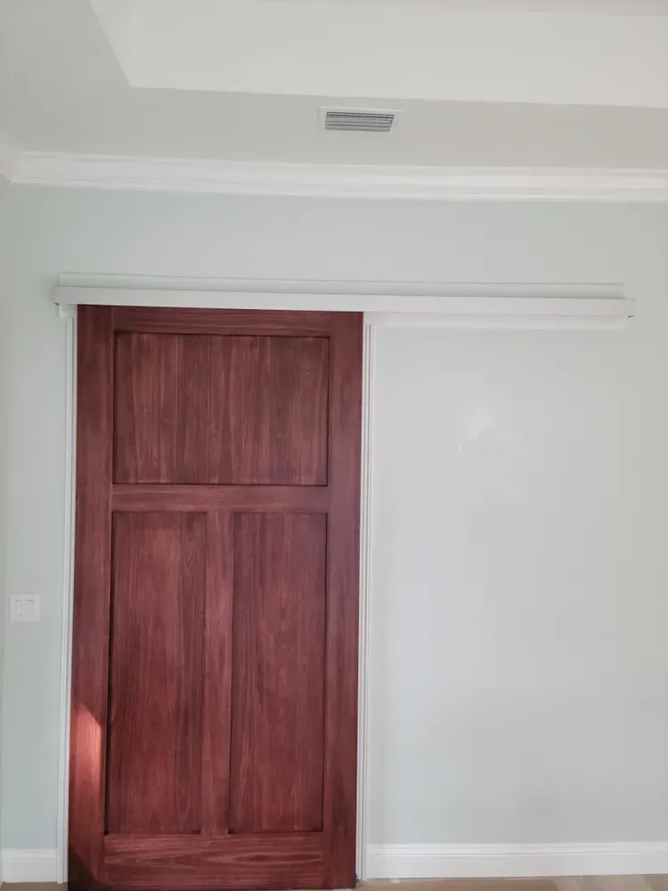 A wooden sliding door in a room with white walls.